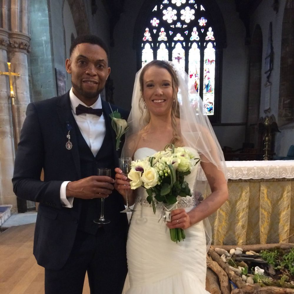 Bridge and groom pictured inside the church holding flowers and a glass of champagne